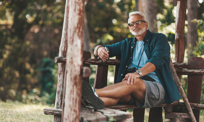 Grandfather is resting in an open gazebo in nature in the forest.