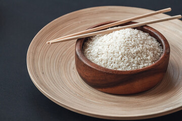White rice in wooden bowl with wooden chopsticks