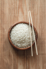 White rice in wooden bowl with wooden chopsticks