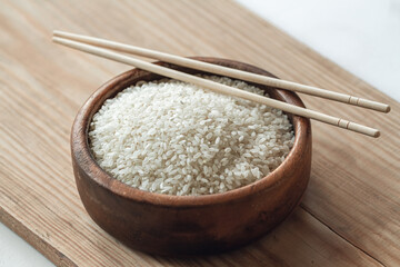 White rice in wooden bowl with wooden chopsticks