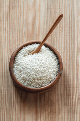 White round rice in a wooden bowl with wooden or bamboo spoon