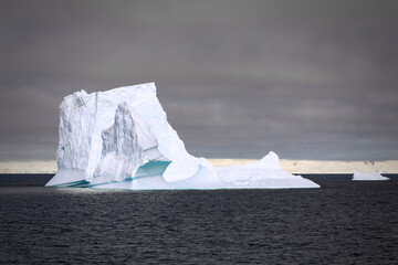 Impressive iceberg with a dark gray sky in the Gerlache Strait in Antarctica.