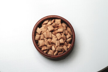 Wooden bowl with chocolate quick breakfast cereal on white background