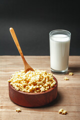Wooden bowl with quick breakfast cereal and glass of milk