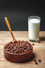 Wooden Bowl with chocolate quick breakfast cereal and glass of milk