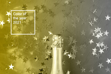Champagne bottle with gold confetti stars. Concept for christmas. Color of the year 2021