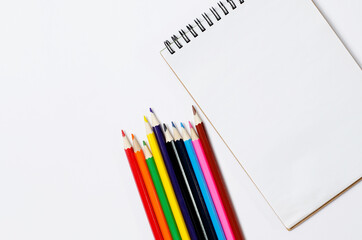 School composition. Consists of pencils and a notebook on a white background. Top view, flat sunbed, space for text.