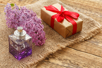 Obraz na płótnie Canvas Gift box with perfume and flowers on the wooden background.