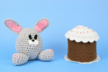 Knitted bunny and Easter cake isolated on light blue background