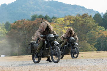 Obraz na płótnie Canvas ギリースーツを着てバイクに乗る歩兵