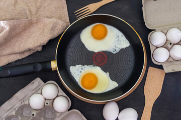 Fried eggs cooking process. Two fried eggs in a pan and raw eggs