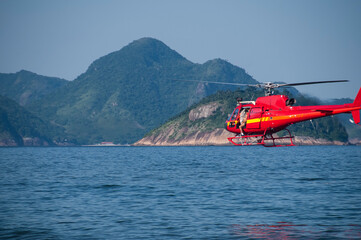 Firefighter-rescuers fly in a helicopter over Ipanema beach, Brazil