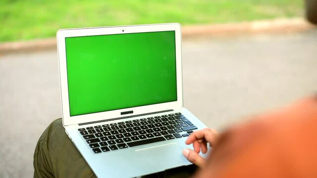 Green screen chroma key laptop blank monitor in park outdoor. Mock-up free content. Traveling freelance business lifestyle. Internet connecting. Online shopping. New education system. Man using tech..