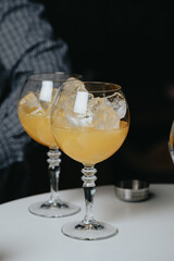 Cocktails with champagne in wine glasses on the bar table in the pub or restaurant with the bartender.