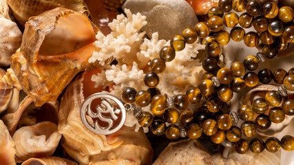 Buddhist prayer beads Mala lying on the sea rocks surrounded by sea shells. close-up