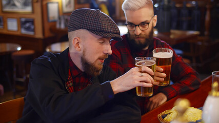 Meeting of two male friends in bar discussing latest news and smiling