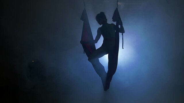 Gorgeous girl showing her flexibility and splits with red aerial silk on the studio background. Healthy lifestyle