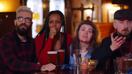 Friends looking disappointed watching sports match on tv together in bar