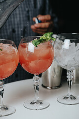 Cocktails with champagne in wine glasses on the bar table in the pub or restaurant with the bartender.