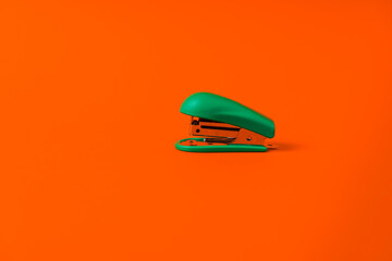 Stationery stapler on an orange background. Minimalism and copy space