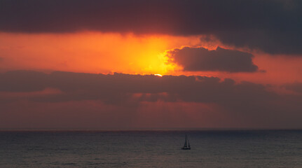 Sailboat goes on the waves during sunset. Seascape