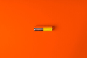 Yellow AA alkaline batteries on an orange background. Popular battery size. Copy the space. - obrazy, fototapety, plakaty