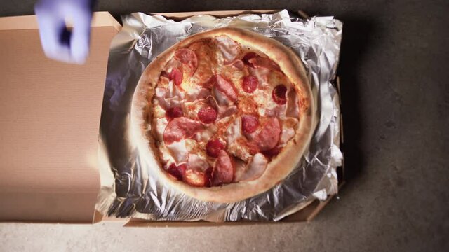 top view, hands of a professional chef puts freshly cooked pizza from the oven into a pizza box, ready for delivery recipe takeaway meat hot eat takeaway box