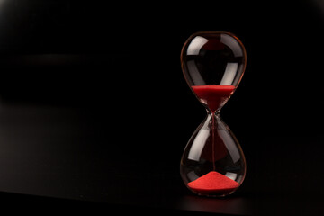 Crystal hourglass on black background as a concept of passing time for business term, urgency and...