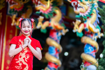 Portrait beautiful smiles Cute little Asian girl wearing red traditional Chinese cheongsam decoration for Chinese New Year Festival at Chinese shrine