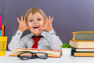 goofy preschool boy is sitting at his Desk