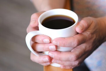 The girl was sitting comfortably in a chair, holding a cup of coffee.