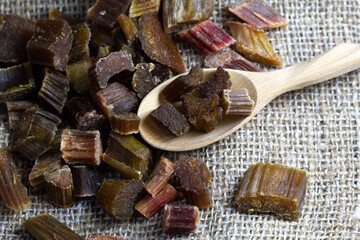Dried rhubarb candied fruits in a wooden spoon. Candied rhubarb on a canvas fabric background. Dry rhubarb close - up macro photography. Rheum.