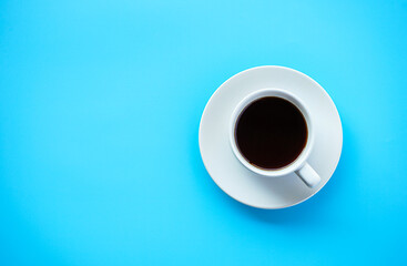 Flat lay view of dark hot coffee cup on blue background with copy space 