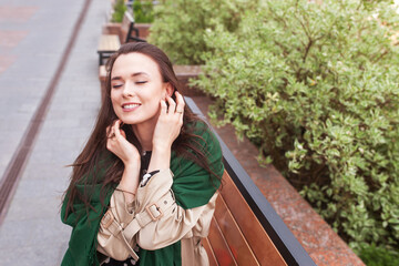 Smiling beautiful girl in the city. Wind developing long hair of happy young woman. Portrait of a cute girl with  closed eyes. Copy space