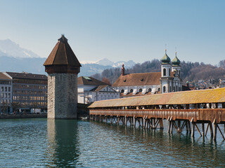 der Wasserturm und die Kapellbrücke (Chapel Bridge) an einem sonnigen Frühlingstag in Luzern, mit der Jesuitenkirche im Hintergrund