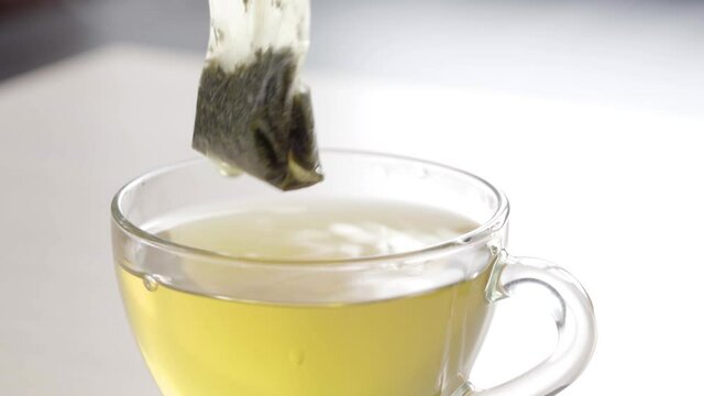 Tea Bag in a Tea Cup. Brew Green Tea in a Mug. White Background