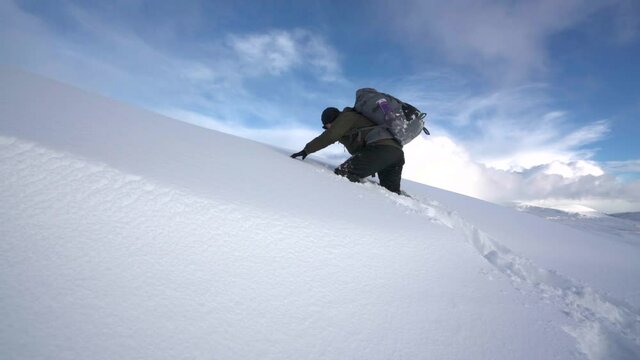 A backpacker climbing through deep mountain snow