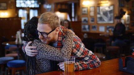Multiethnic couple meeting and hugging in modern beer pub