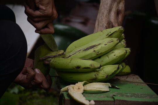 Close-up of a man's hand cutting a banana with a knife