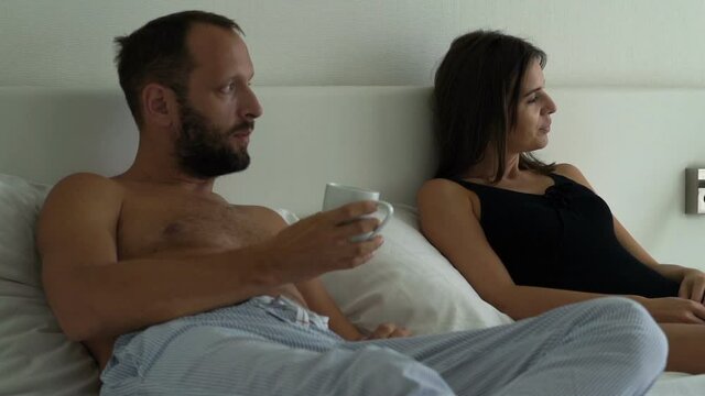 Young unhappy married couple fighting, having problems in bed at apartment