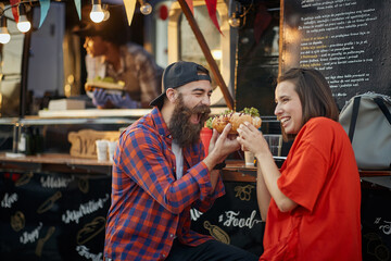 cute caucasian couple are about to eat one sandwich together