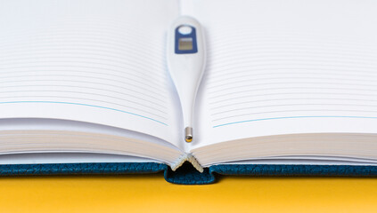 Thermometer on the pages of an open notebook. Temperature measurement recording concept.