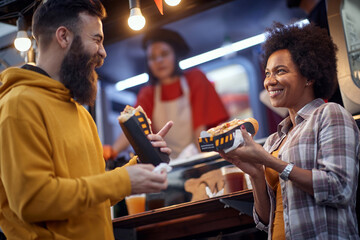friends having a good time while eating sandwiches in front of fast food service