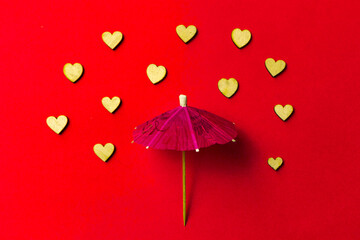 Pink umbrella with heart raindrops on a red background. Copy space. Congratulations to Valentine's day and wedding.