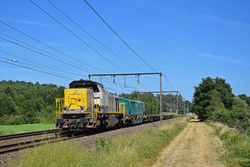 Fototapeta na wymiar LINEAS Diesel Railway Locomotive HLR 77 with short Freight Train under Blue Sky in Langdorp on Double Track Railway Line in Langdorp, Belgium