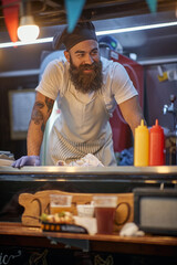 young hipster working in fast food service, wearing cook hat