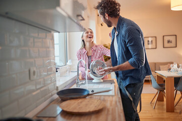 Joyful couple doing the dishes together - 407699036