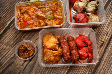 Top view of traditional Indian food in a plastic box on a wooden table. Indian fast food delivery at home. Eat at home.