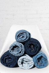 close up view of rolled jeans on white chair near brick wall
