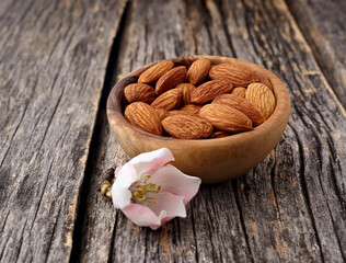 Almond nuts with flowers in closeup isolated on wooden background.